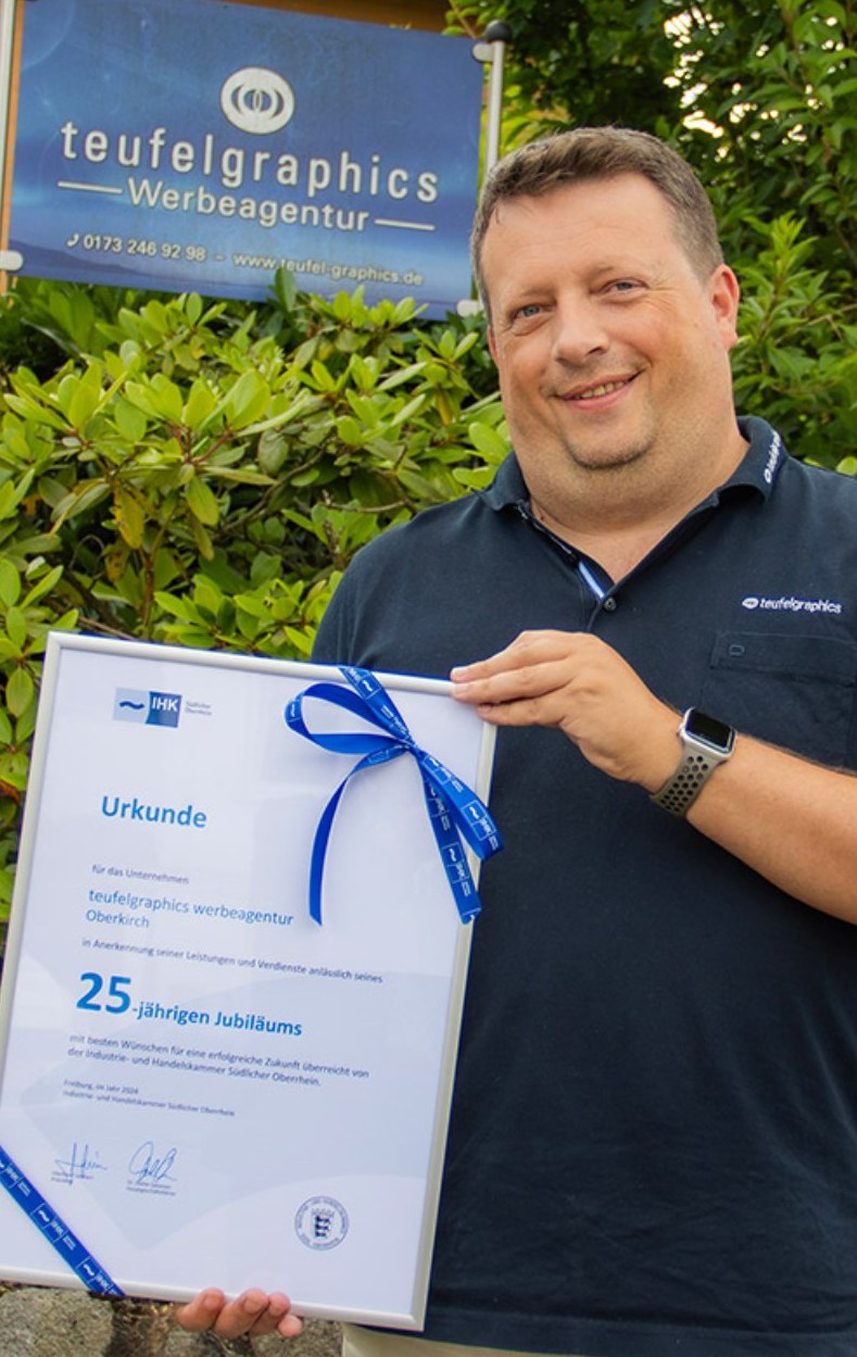 Simon Teufel mit der IHK-Urkunde zum 25-jährigen Jubiläum von teufelgraphics